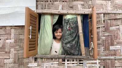 A young girl stands at the window in her house.