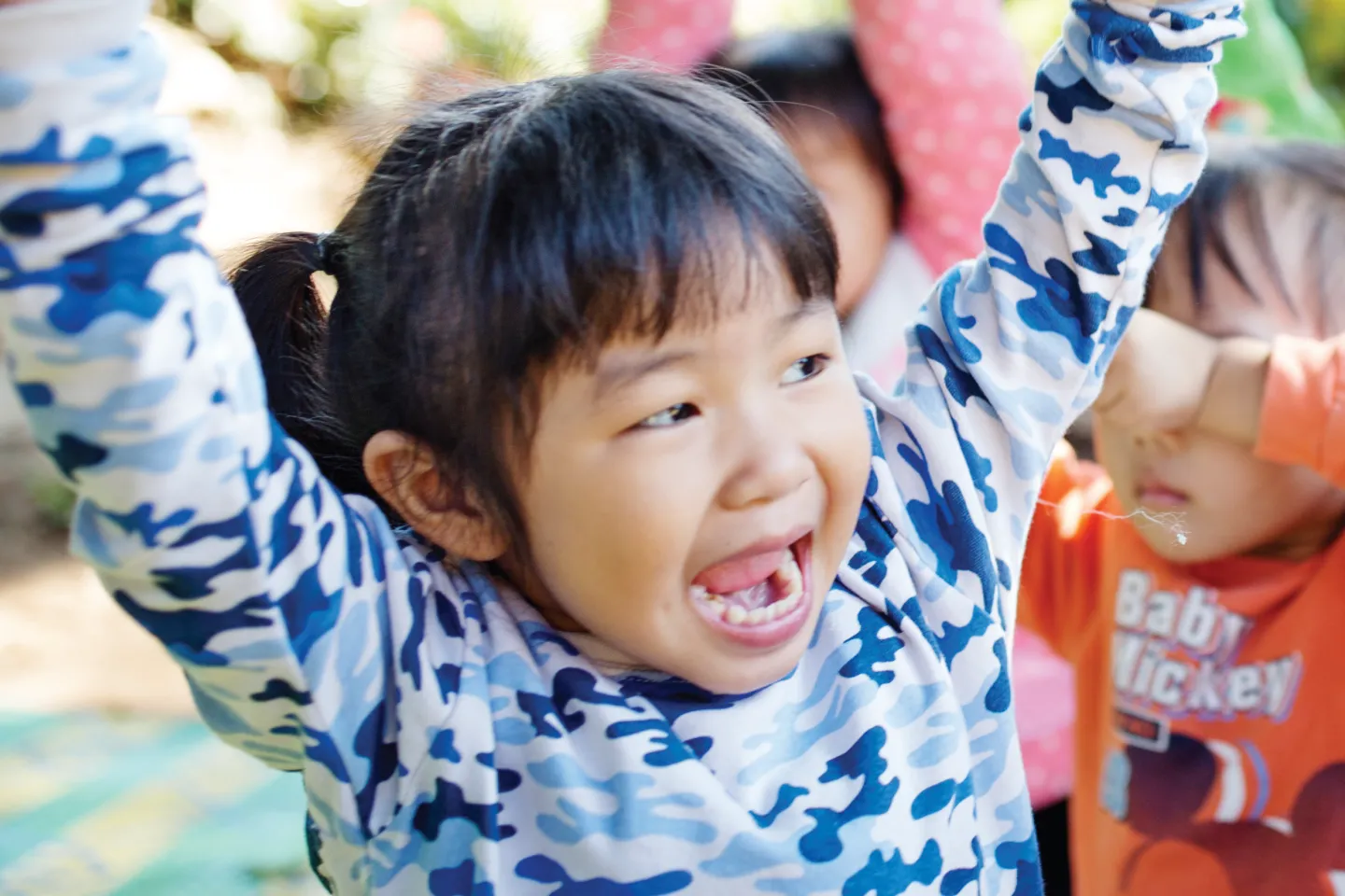 A young child is raising hands up.