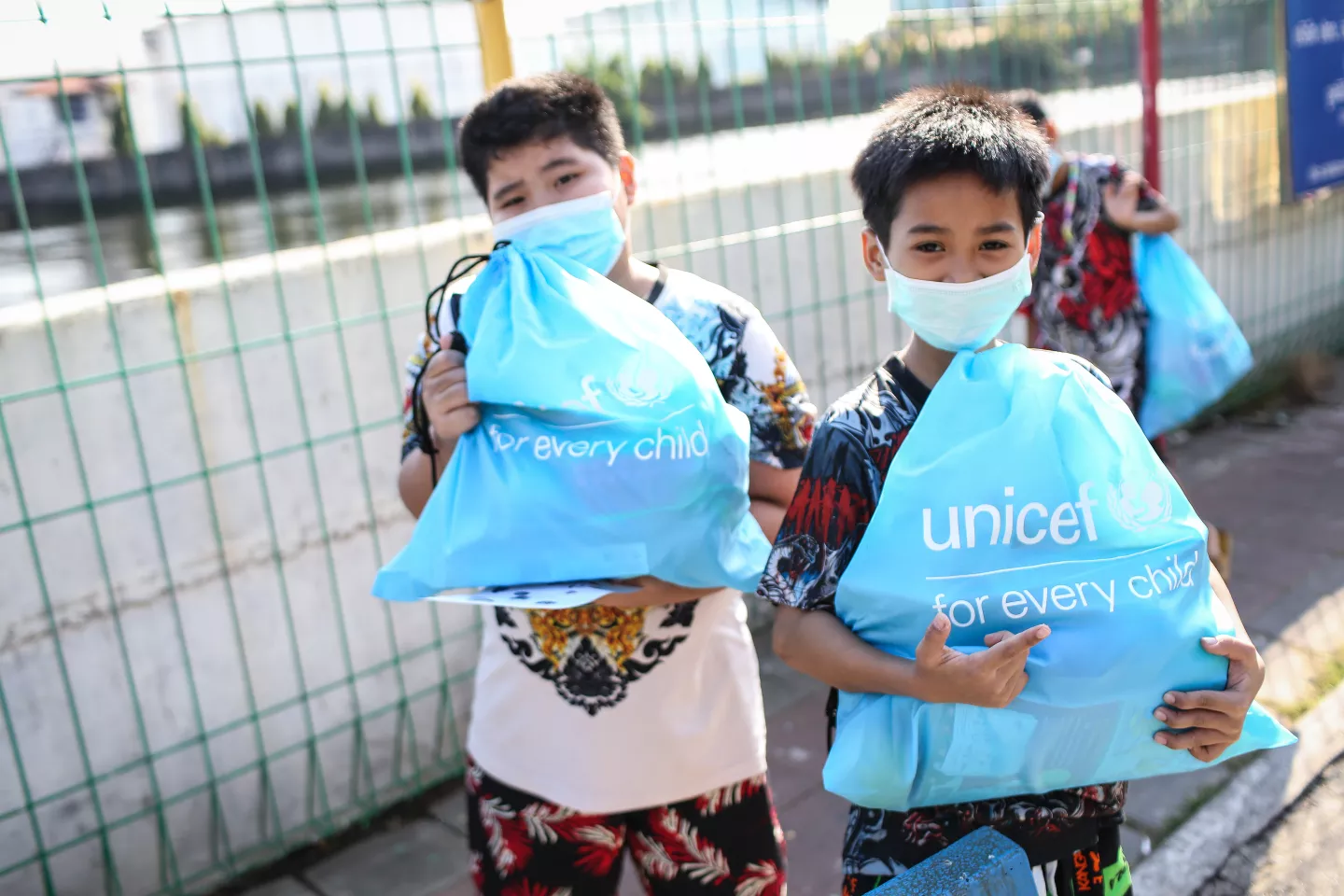 2 boys holding UNICEF's magic bags containing books, toys, crayons and other learning materials.