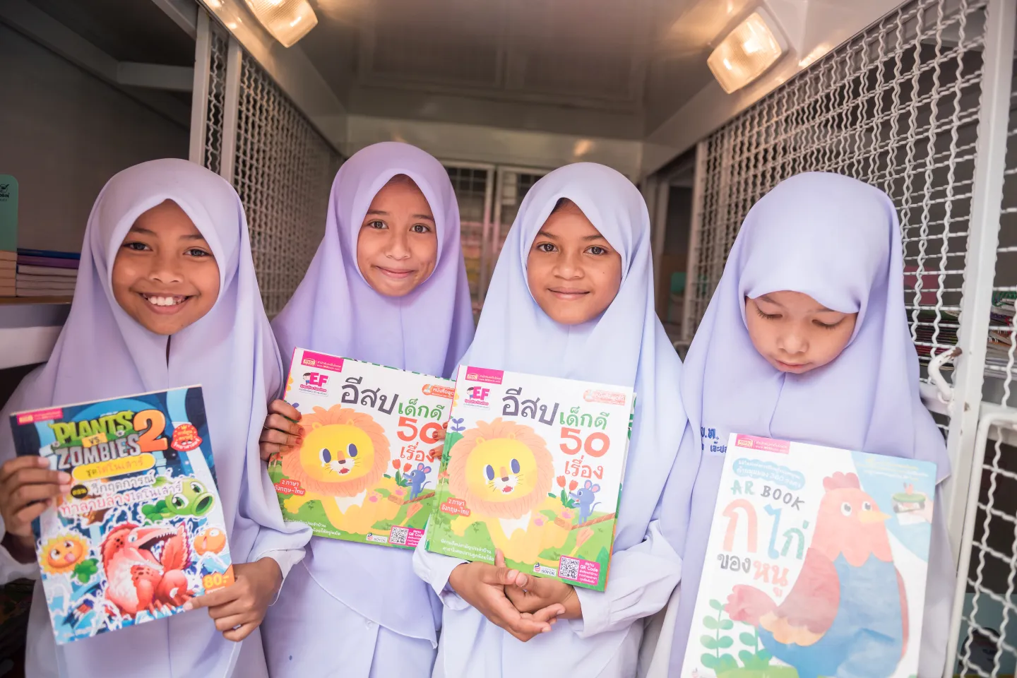 4 students are choosing their favourite books from UNICEF mobile library.