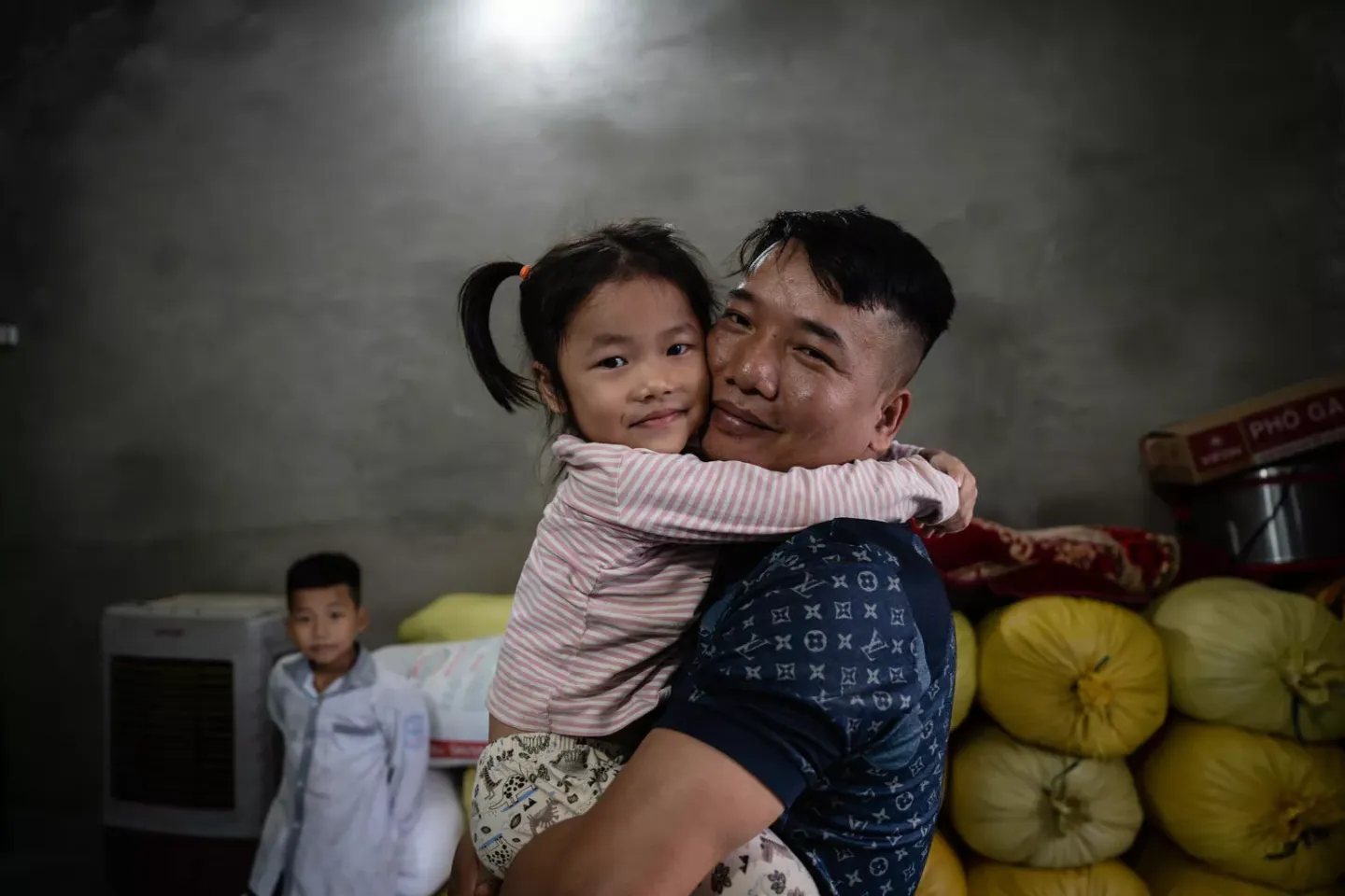 Luu Ton Bay hugs his daughter Luu Thi Ngoc Thuy (4) in their family home