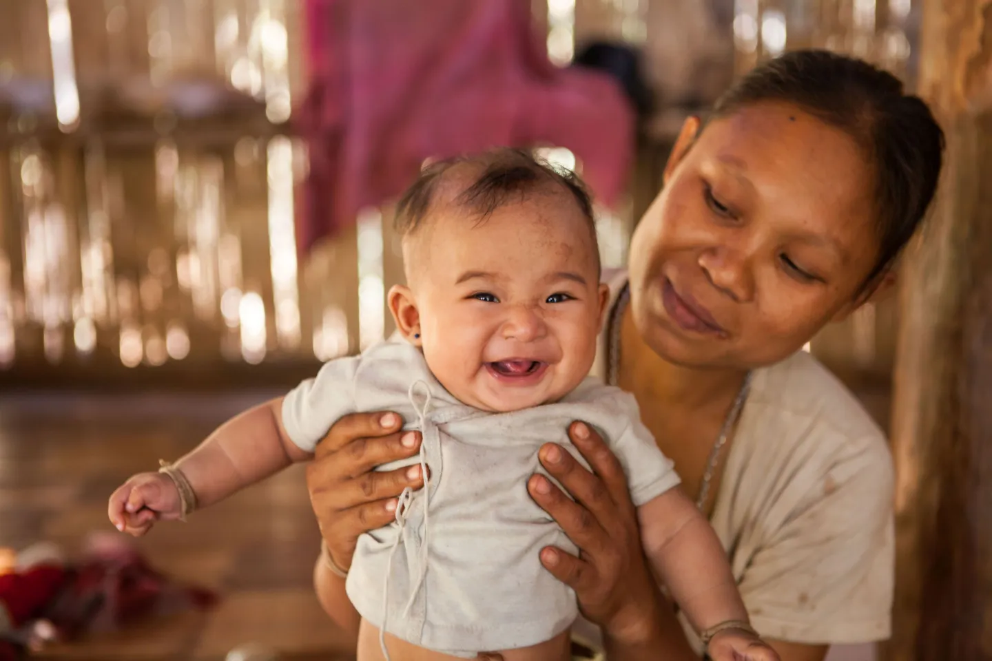 A mother is holding her young baby, who is smiling.