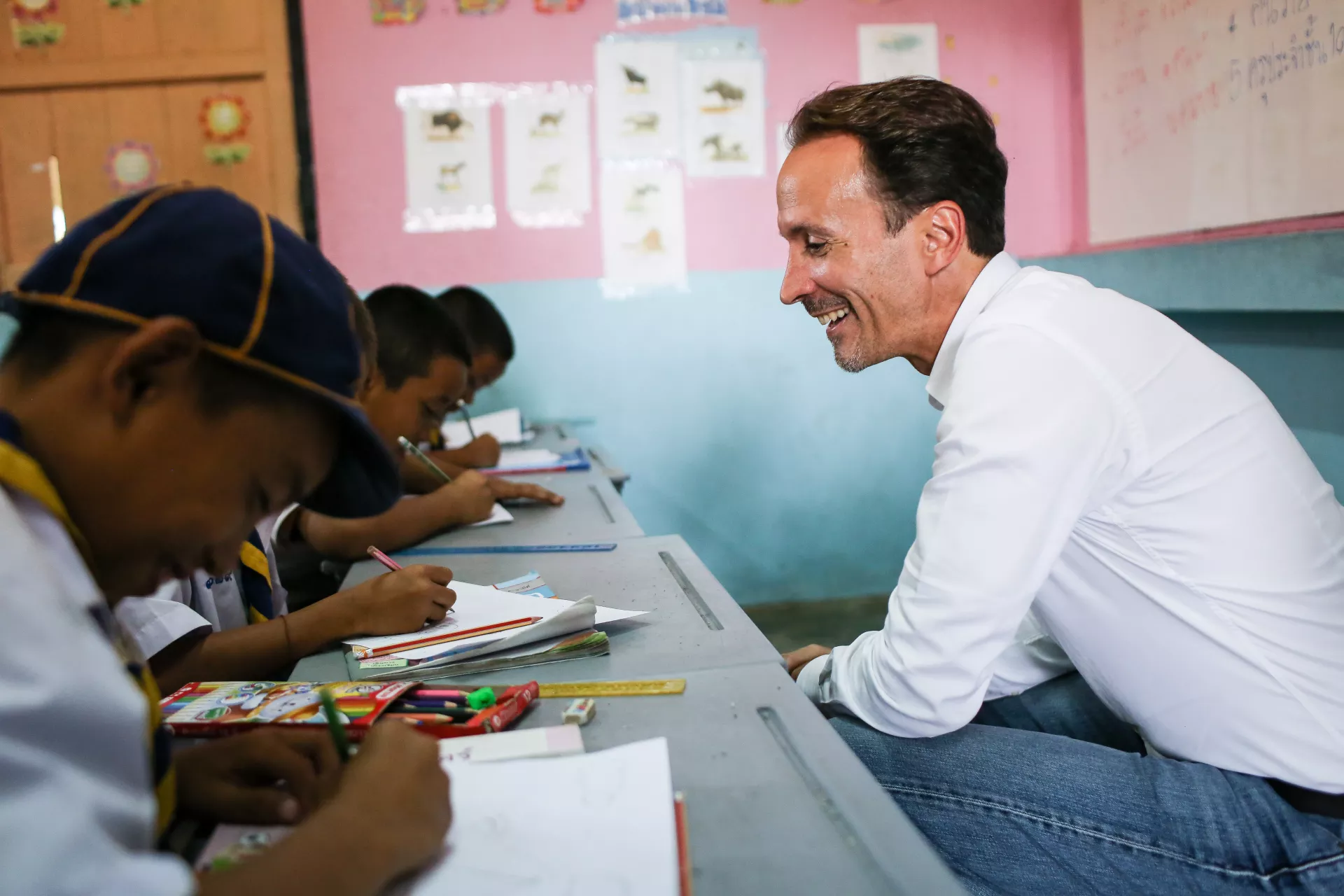 Thomas Davin, the Representative for UNICEF Thailand, is sitting next to a group of children who are studying in the classroom.
