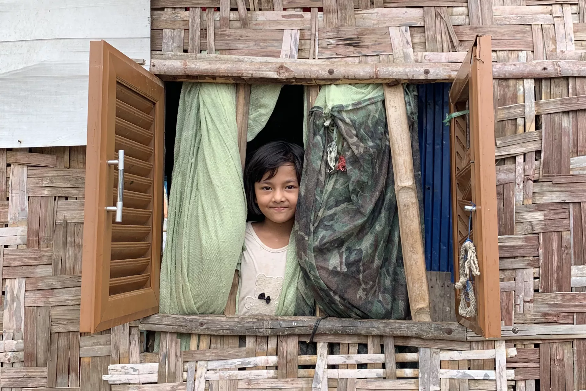 A young girl stands at the window in her house.