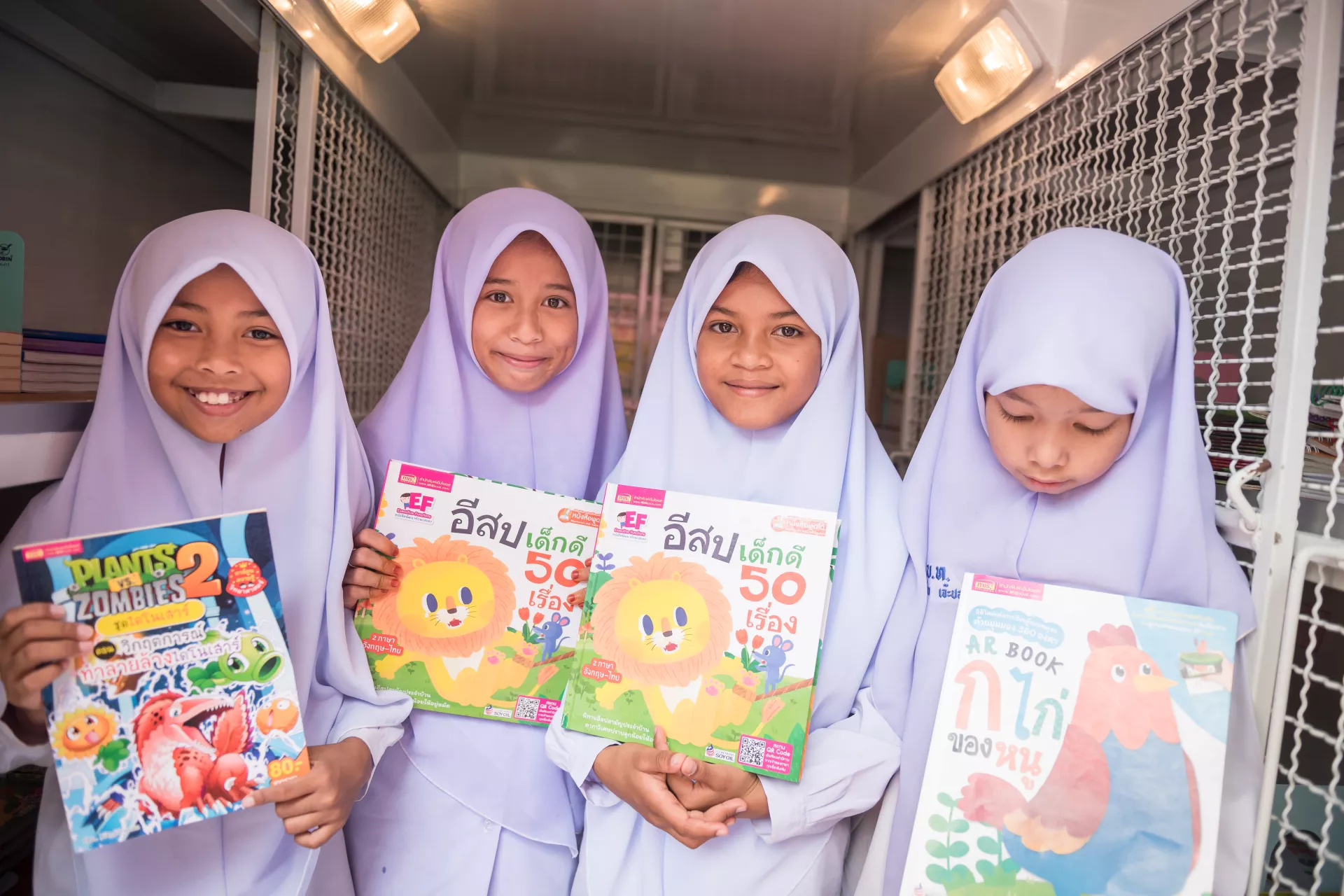 4 students are choosing their favourite books from UNICEF mobile library.