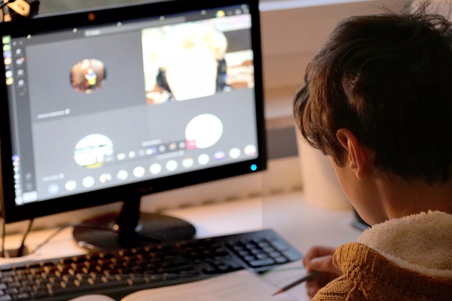A young boy is using an online meeting software to learn online.