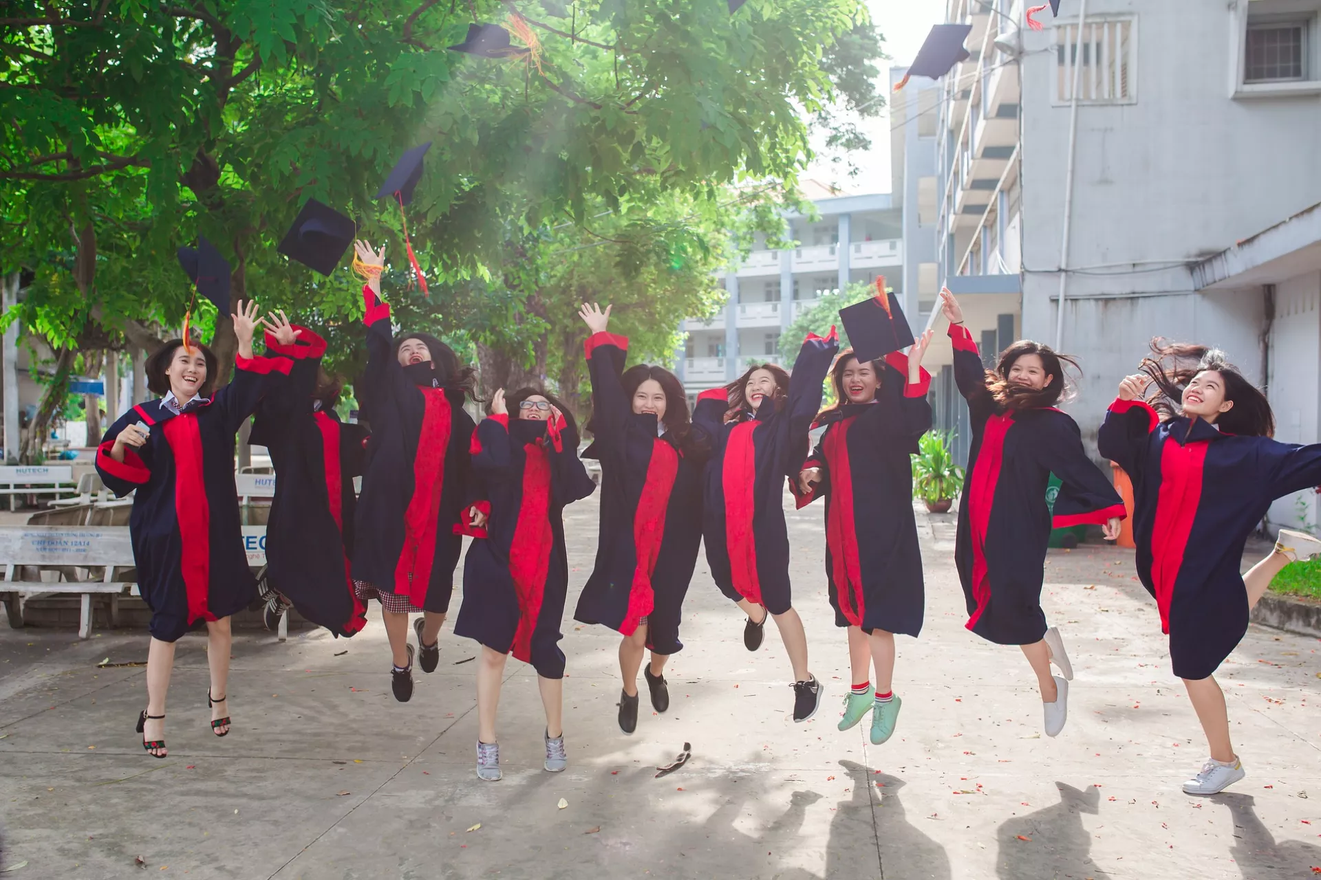 A group of graduated students are jumping happily after the graduation ceremony