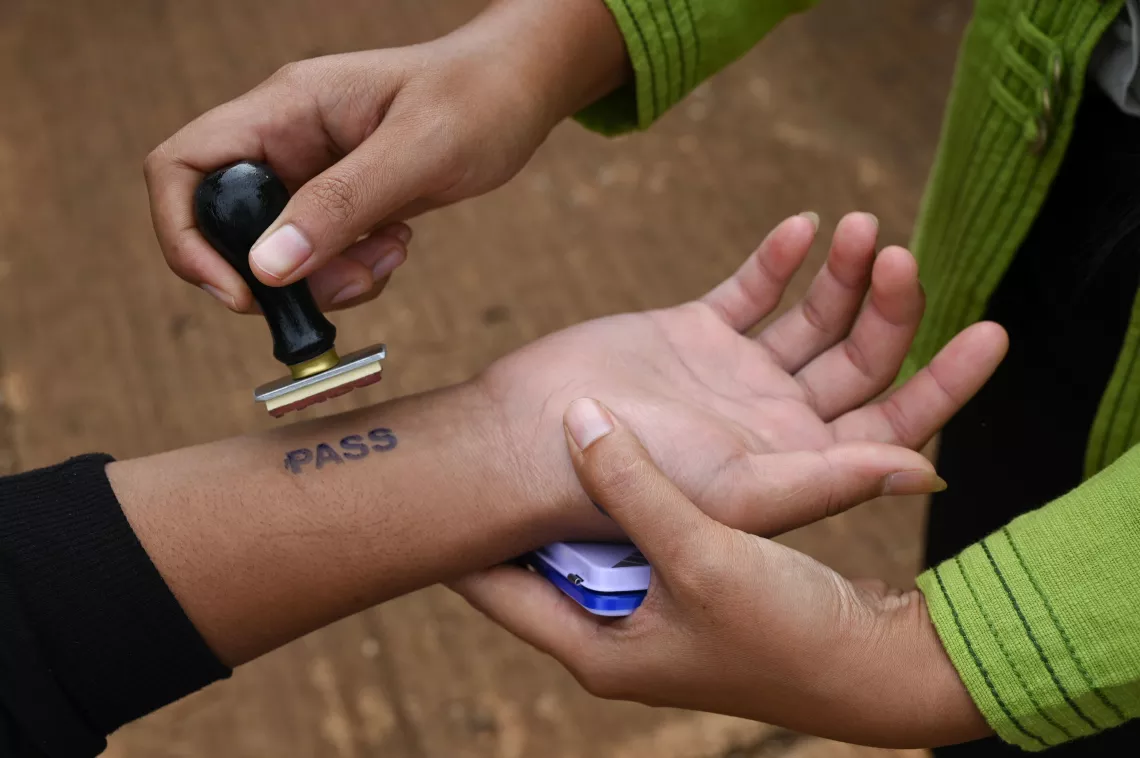 Students who pass the screening area will get "PASS" stamp on one of their wrist.