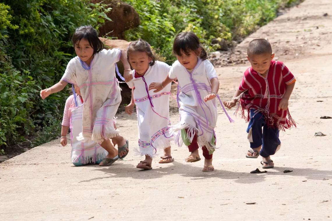 Boys and girls in their hill-tribe dress are playing together.