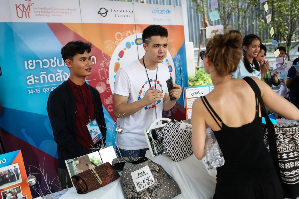 Two young male is talking to a foreign women about their team's idea and products.