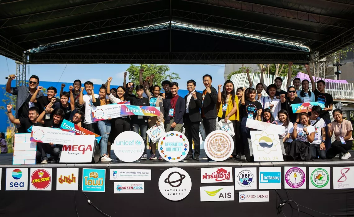 A big group of people are standing on the stage. They are raising their hands to show how energetic they are during their participation in the event.
