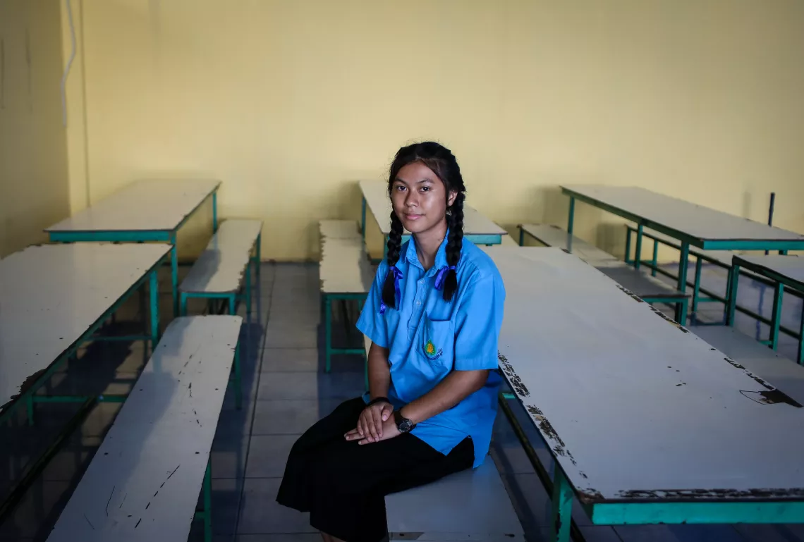 ภาพของบัวผัด ลุงซอ กำลังนั่งอยู่บนเก้าอี้ในโรงอาหาร