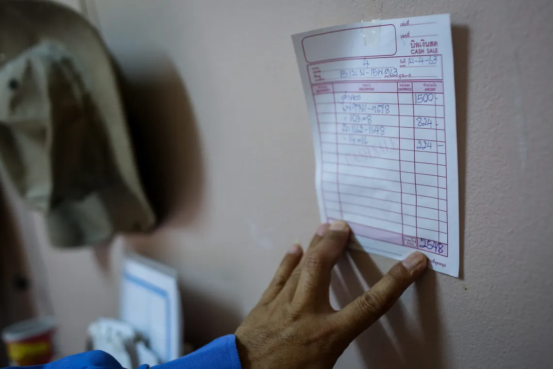A hand touching a note that shows the amount of fee for electric and water bills.