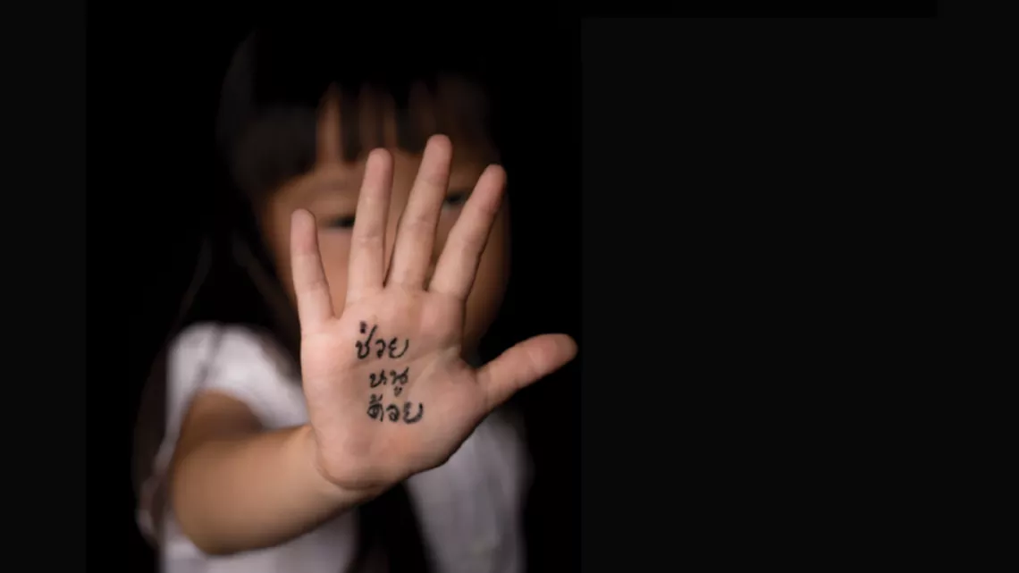 A young girl stretching out her right hand. "Help me" is written on her hand.