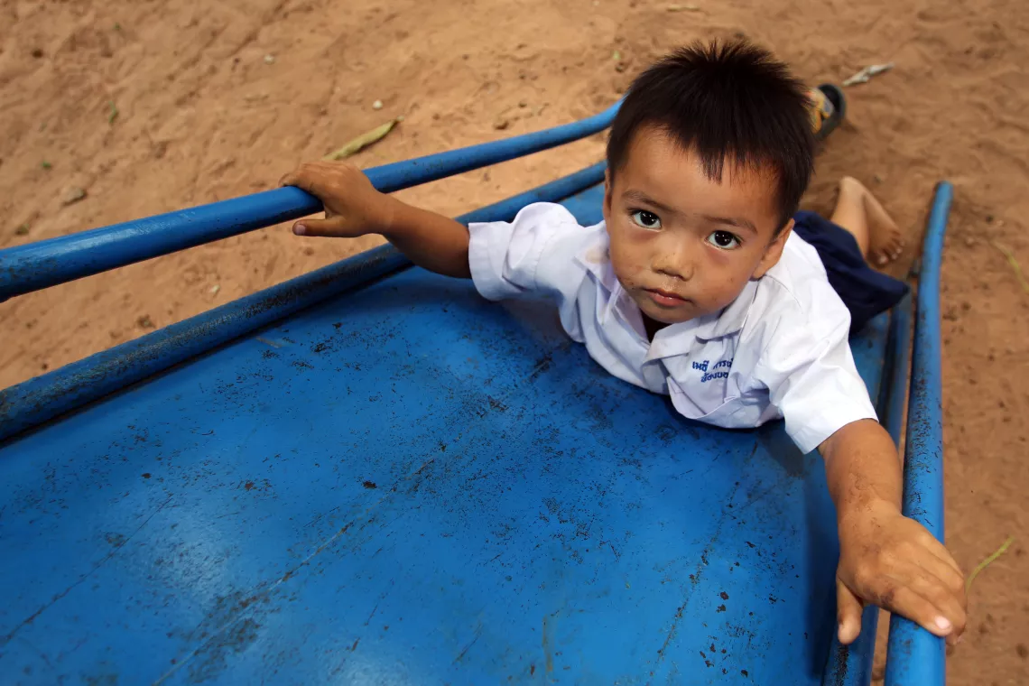 A young boy is play a slider, looking towards the camera.