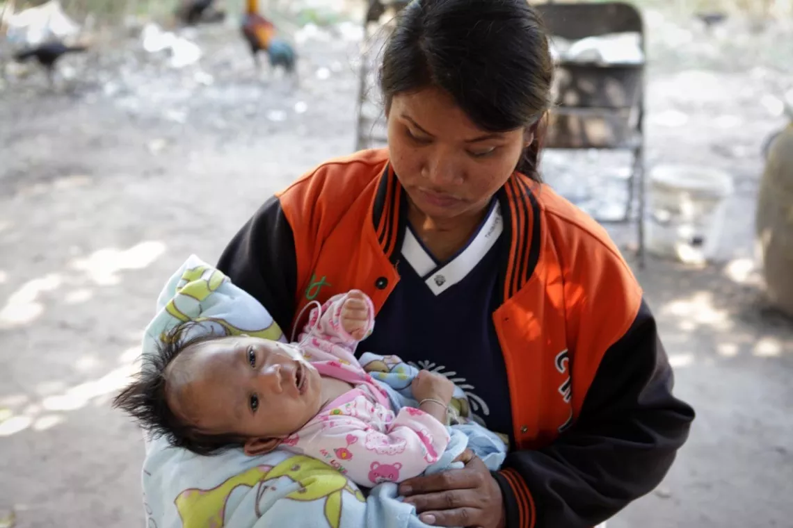 A mother is holding her baby in her arms