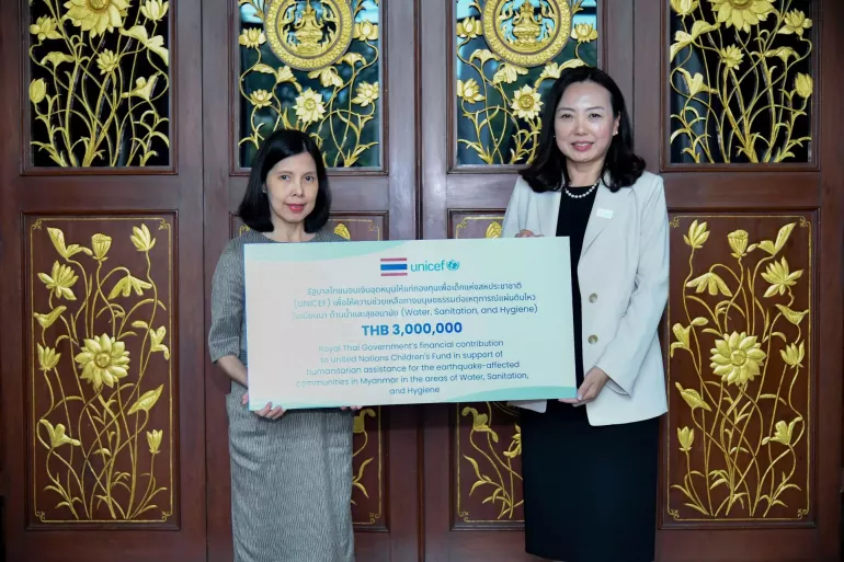 Two women stand holding a large sign with UNICEF and Thai government logos, announcing a THB 3,000,000 donation for humanitarian aid in Myanmar.