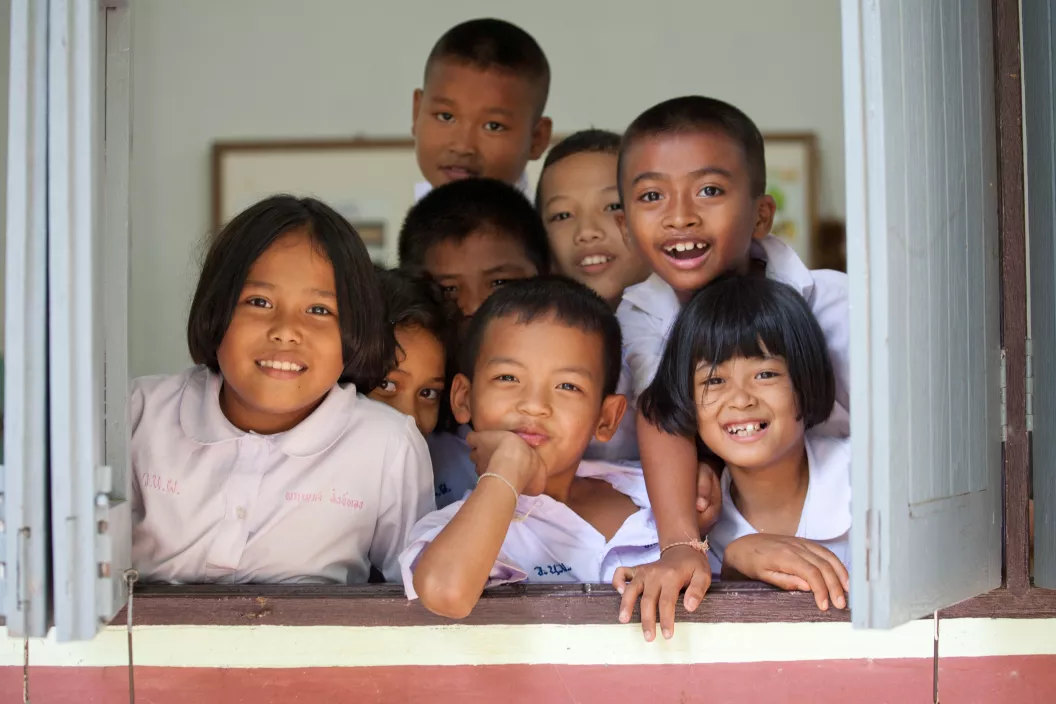กลุ่มของเด็กนักเรียนกำลังยิ้มอยู่ตรงหน้าต่างของห้องเรียน