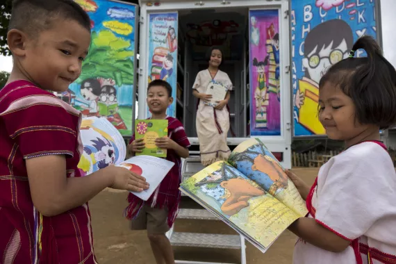 A group of hilltribe children are reading books at the back of UNICEF's mobile library