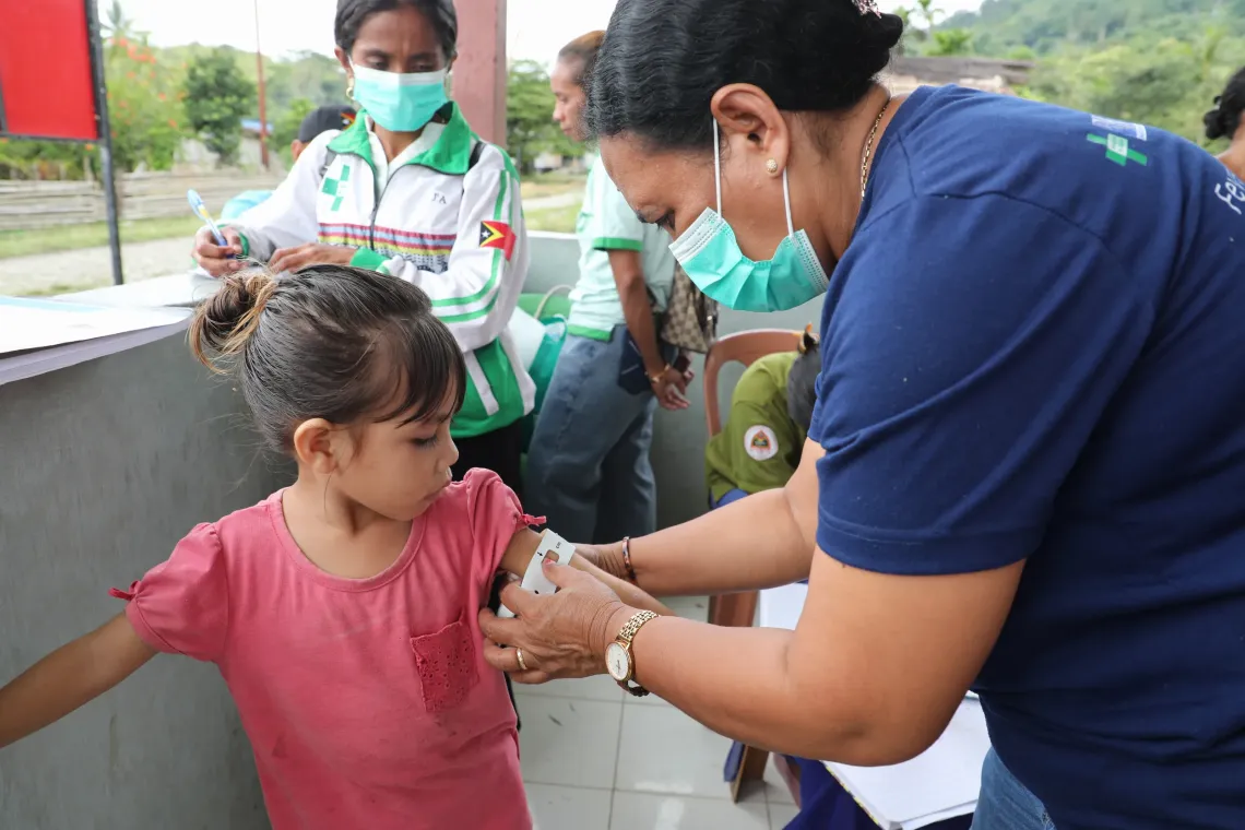 Zenesia is getting a Mid-Upper Arm Circumference (MUAC) screening to check nutritional status.