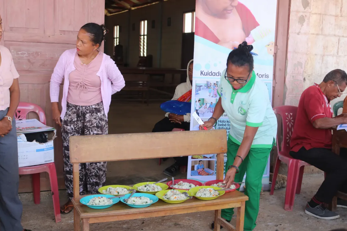 Miranda distributes micronutrient powder and explains how to cook porridge using local produce. 