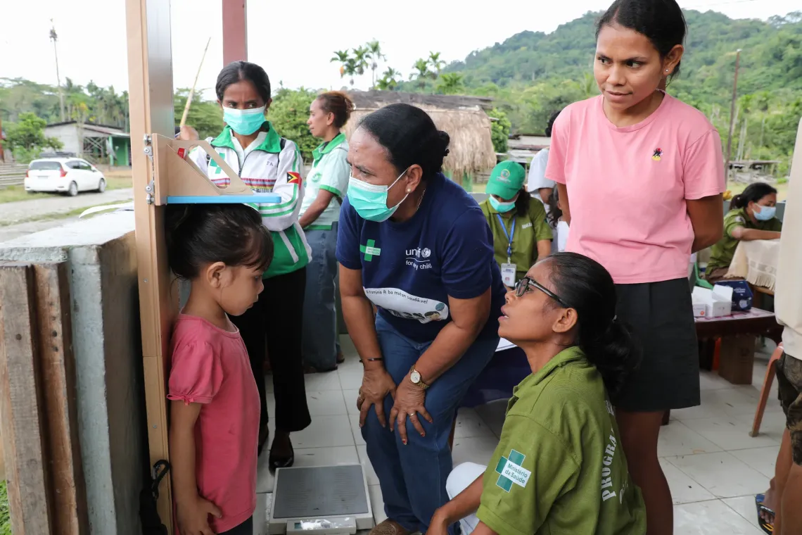 Five-year-old Zenesia is getting measured by a Nurse and a Nutritionist during the outreach session in Searema village