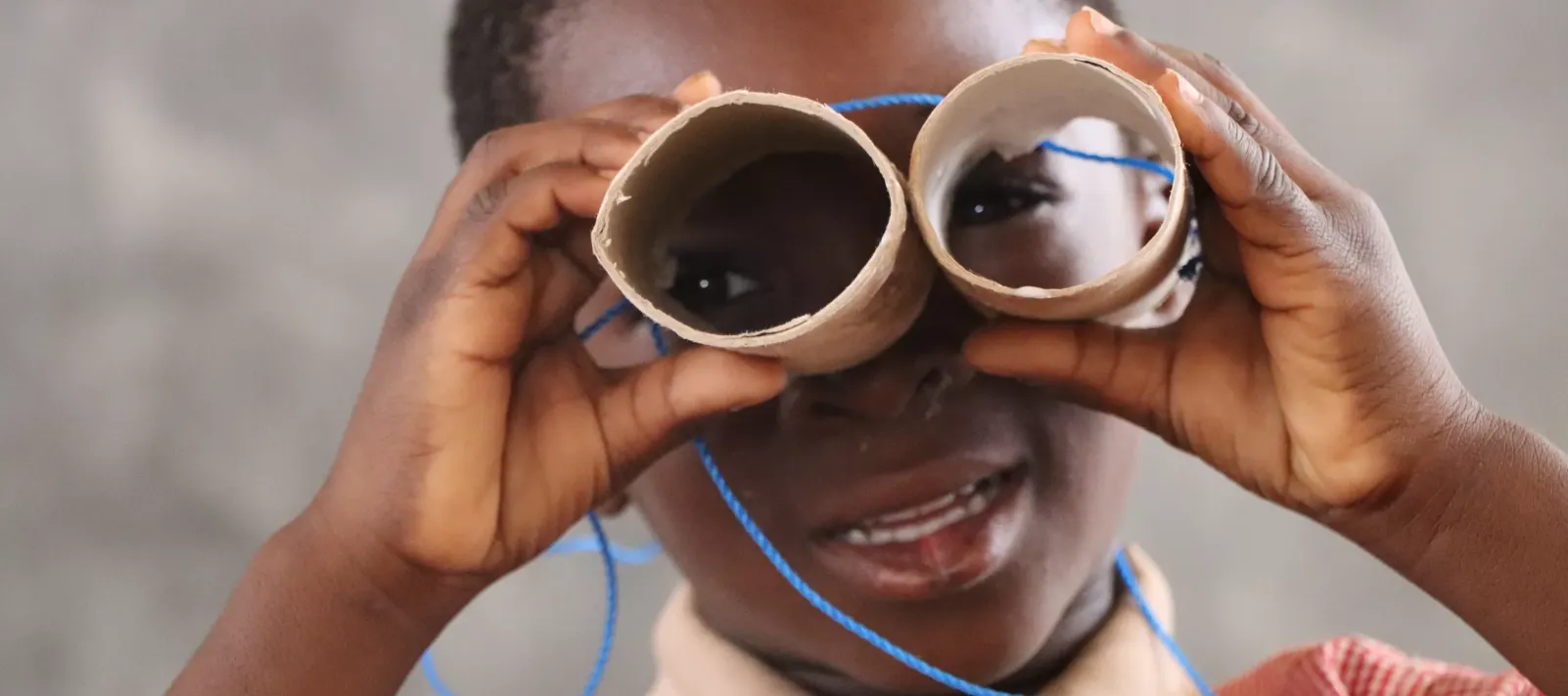 Un enfant avec une paire de rouleaux de papier toilettes transform&eacute;s pour des jeux &eacute;ducatifs