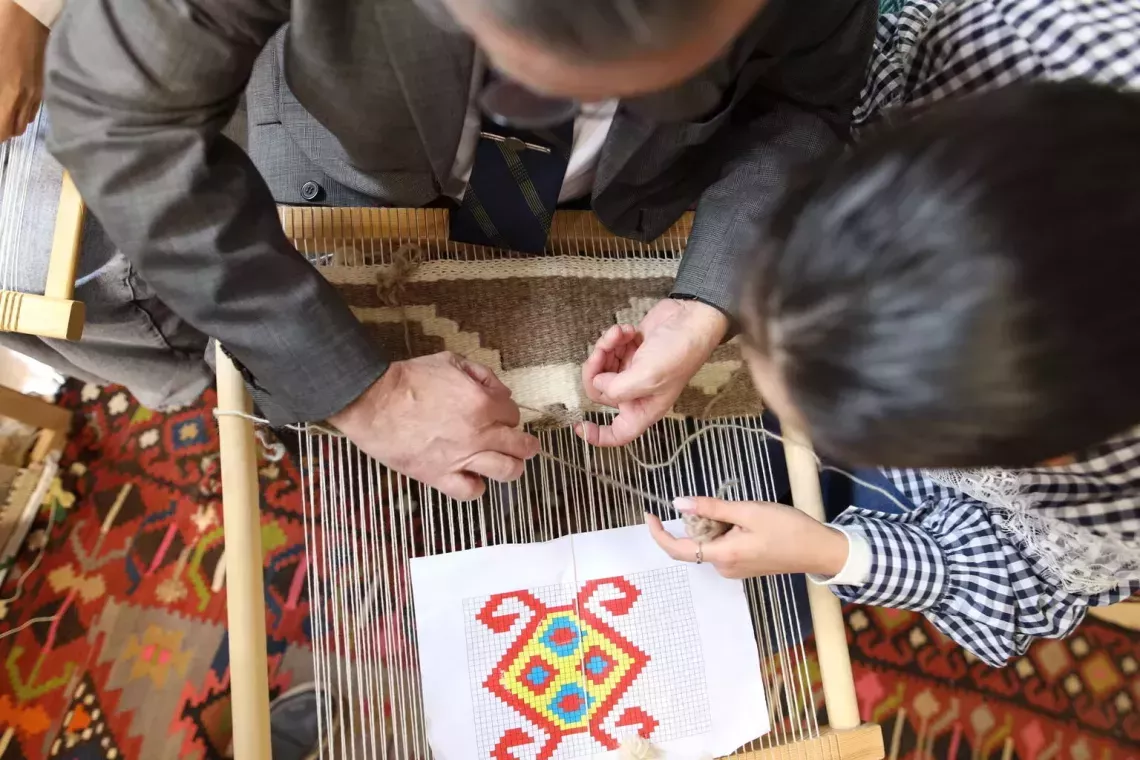 Two people are crafting a fabric