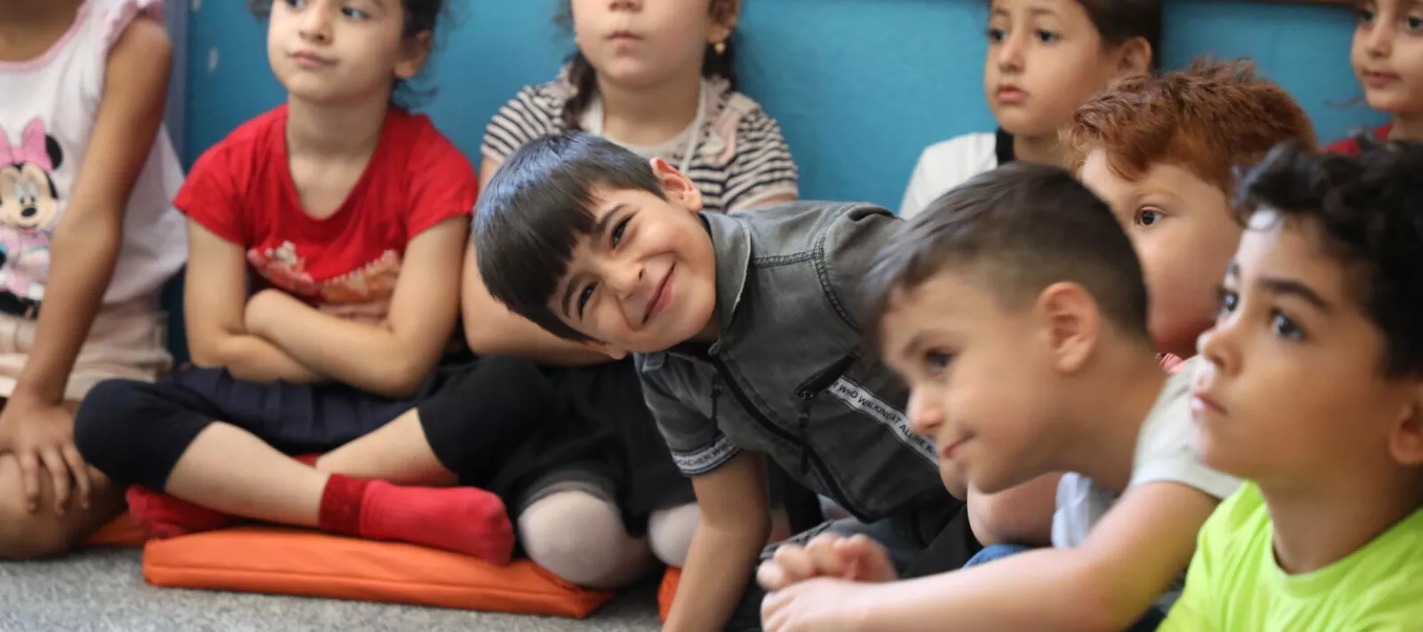Children sitting on the floor in the kindergarden and posing to camera. 