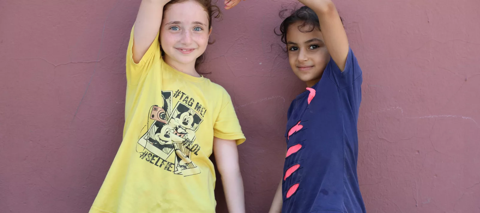 Two girls making a heart with their hands. 