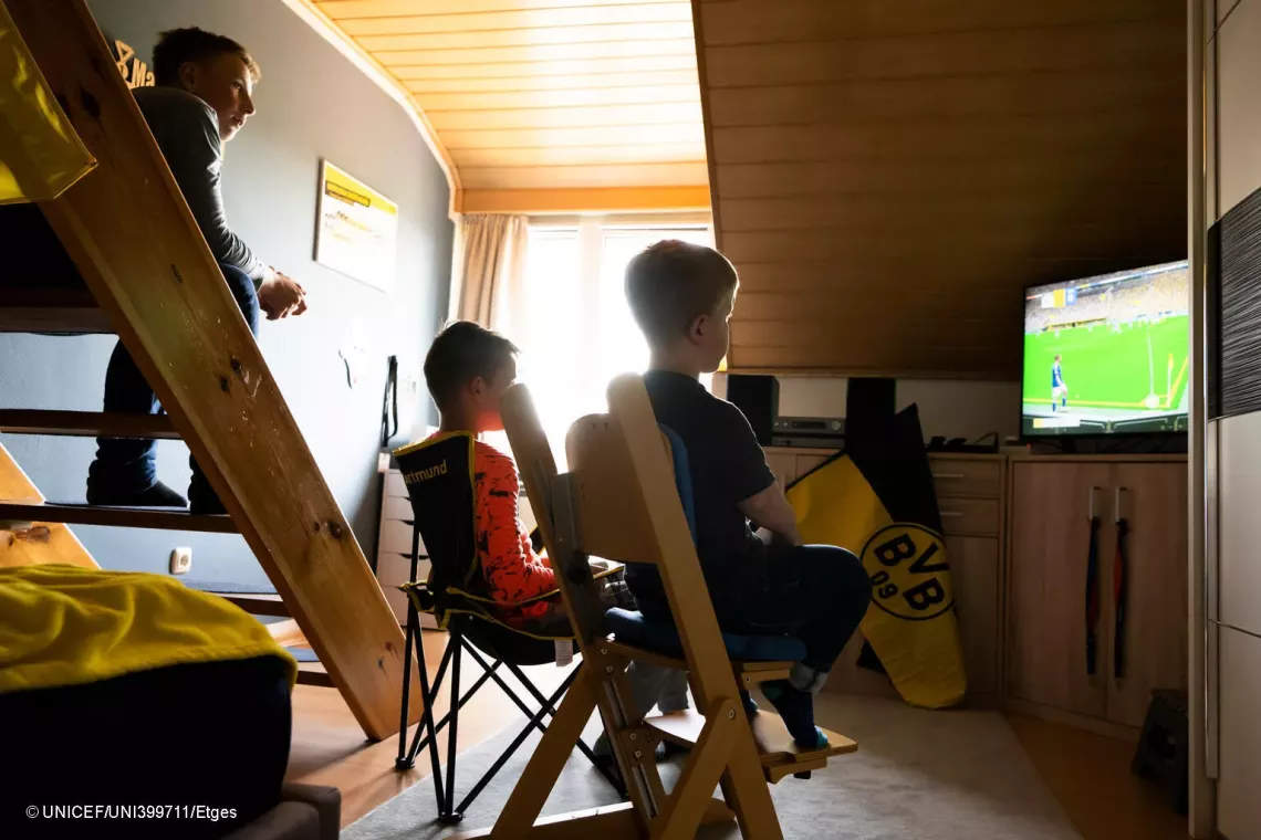 3 erkek &ccedil;ocuğu televizyonda bir futbol oyunu oynuyor. 
