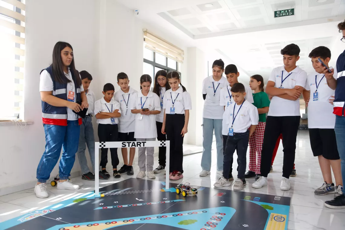 Gen&ccedil;ler bir araya toplanıp arabaları inceliyor. 