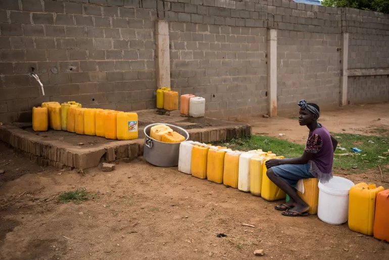 A girl sits at a water tap with a jerry cans lined up in a queue outside a private business on the outskirts of Juba, South Sudan. 