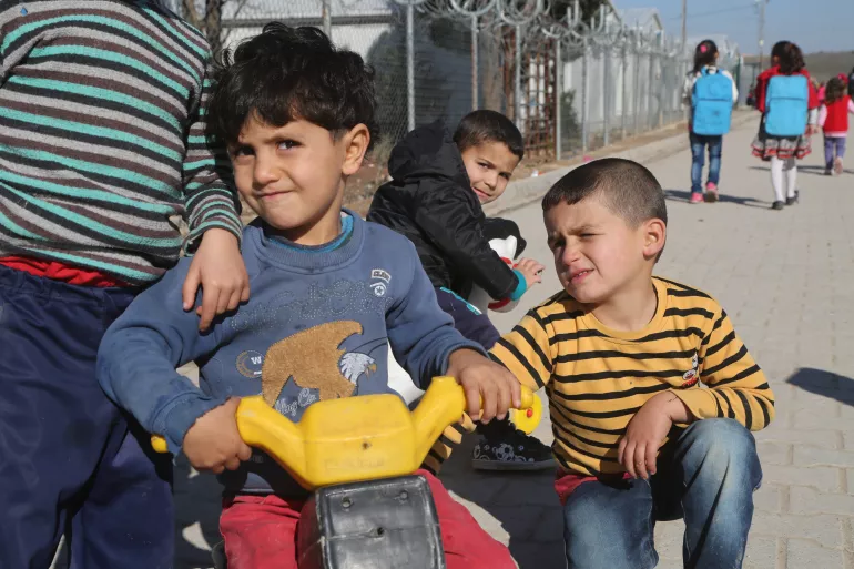 Syrian refugee boys racing their tricycles 