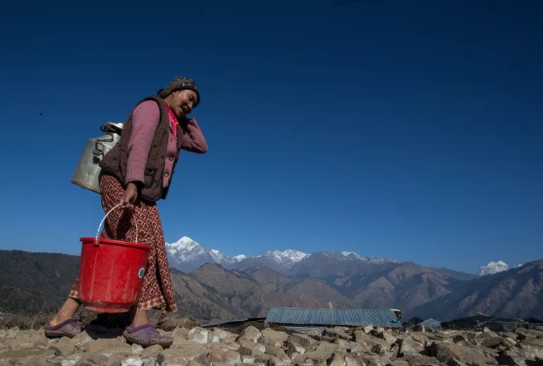 On 16 January 2016, Maya Gurung, aged 30, carries drinking water as she walks to her temporary shelter in Gupsi Pakha, in Laprak, in Gorkha district, Nepal