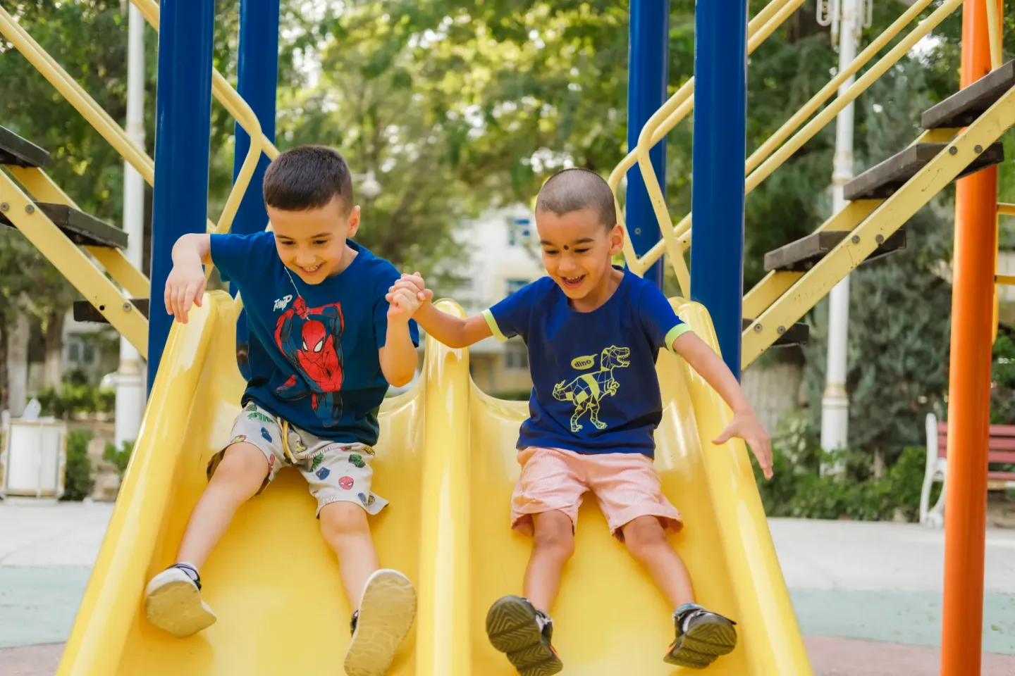 Two boys sliding down the slide
