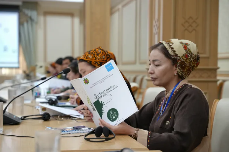 A meeting participant reviewing a printed copy of the "Green School" program guidelines during a workshop session.
