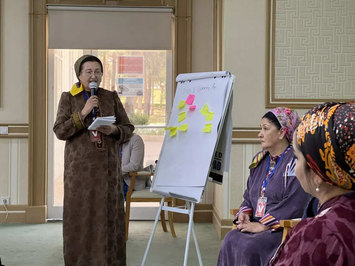 A standing woman speaking two other speaking women
