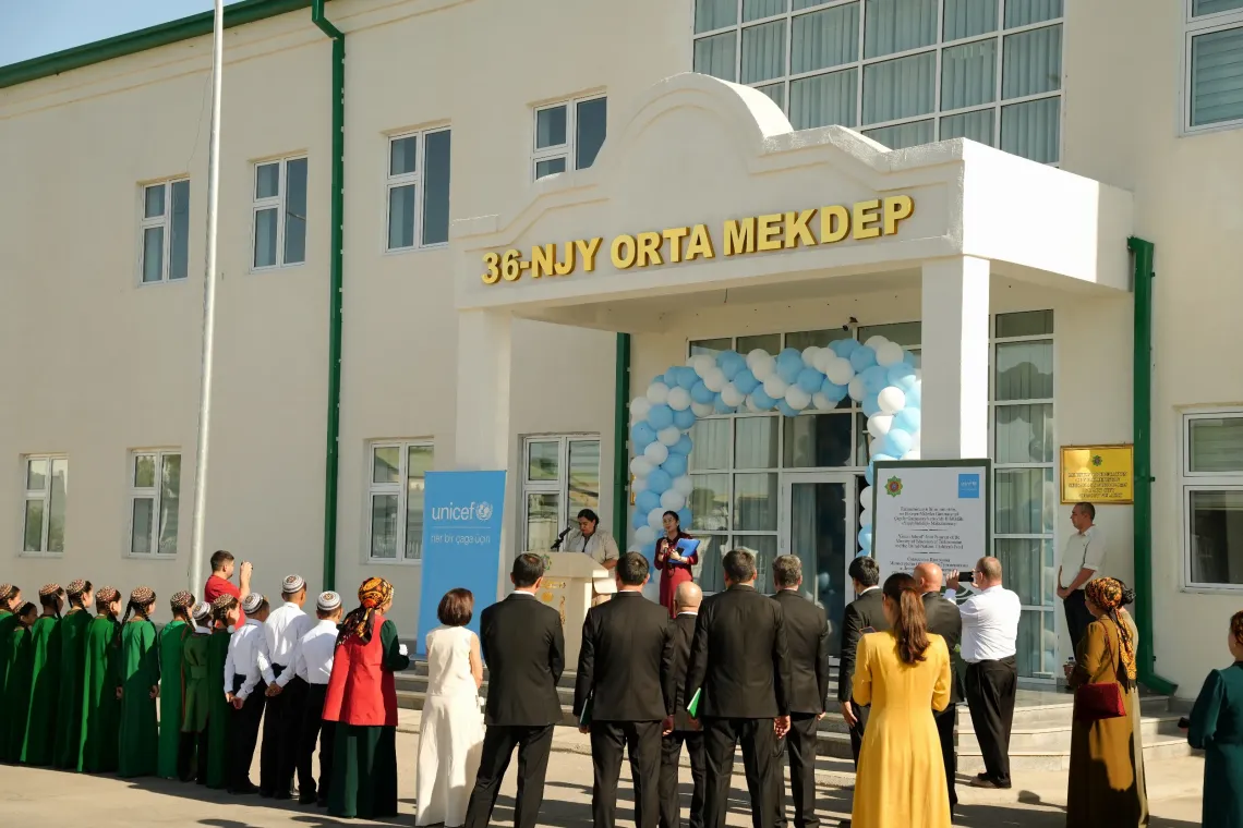 Wide view of the entrance of Secondary School No. 36 in Mary decorated with a balloon arch, with participants gathered to hear the opening remarks.