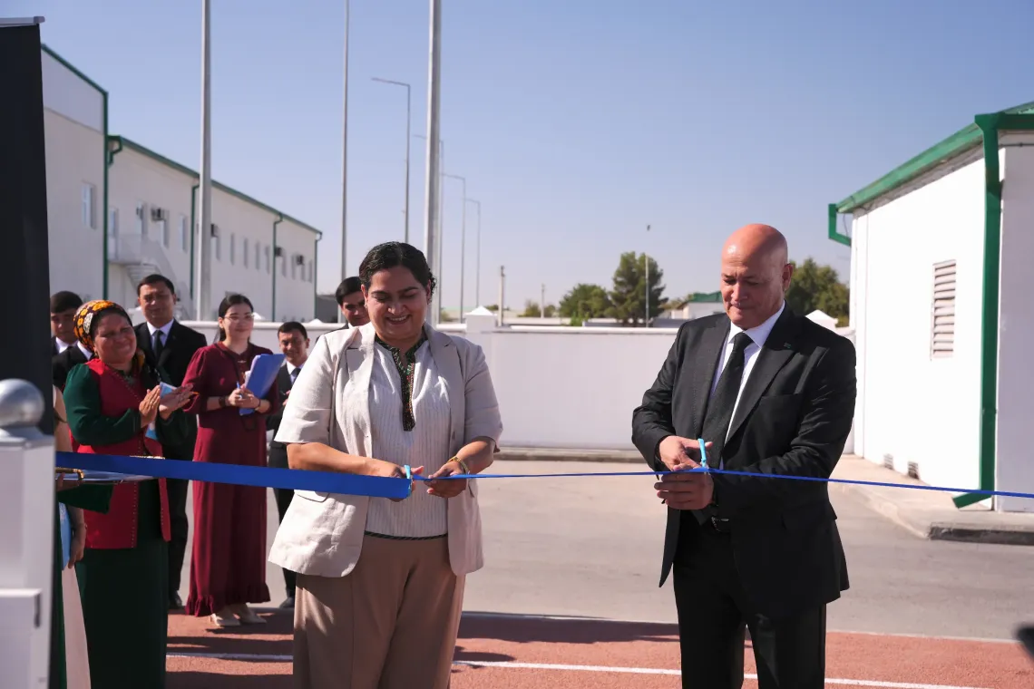 UNICEF Representative Jalpa Ratna and an education official cutting the ceremonial blue ribbon to open the new solar power station.
