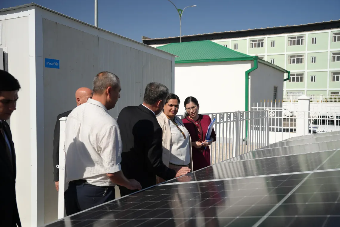 Officials and engineers examining the newly installed ground-mounted solar photovoltaic panels behind a security fence.