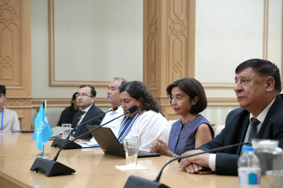UNICEF Representative Jalpa Ratna and meeting participants seated at a conference table with a small UNICEF flag during a youth climate event.