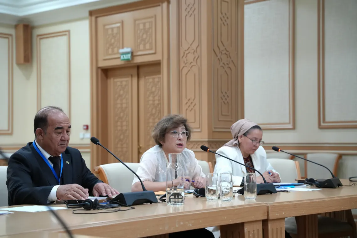 A woman speaking into microphone besides her two other participants