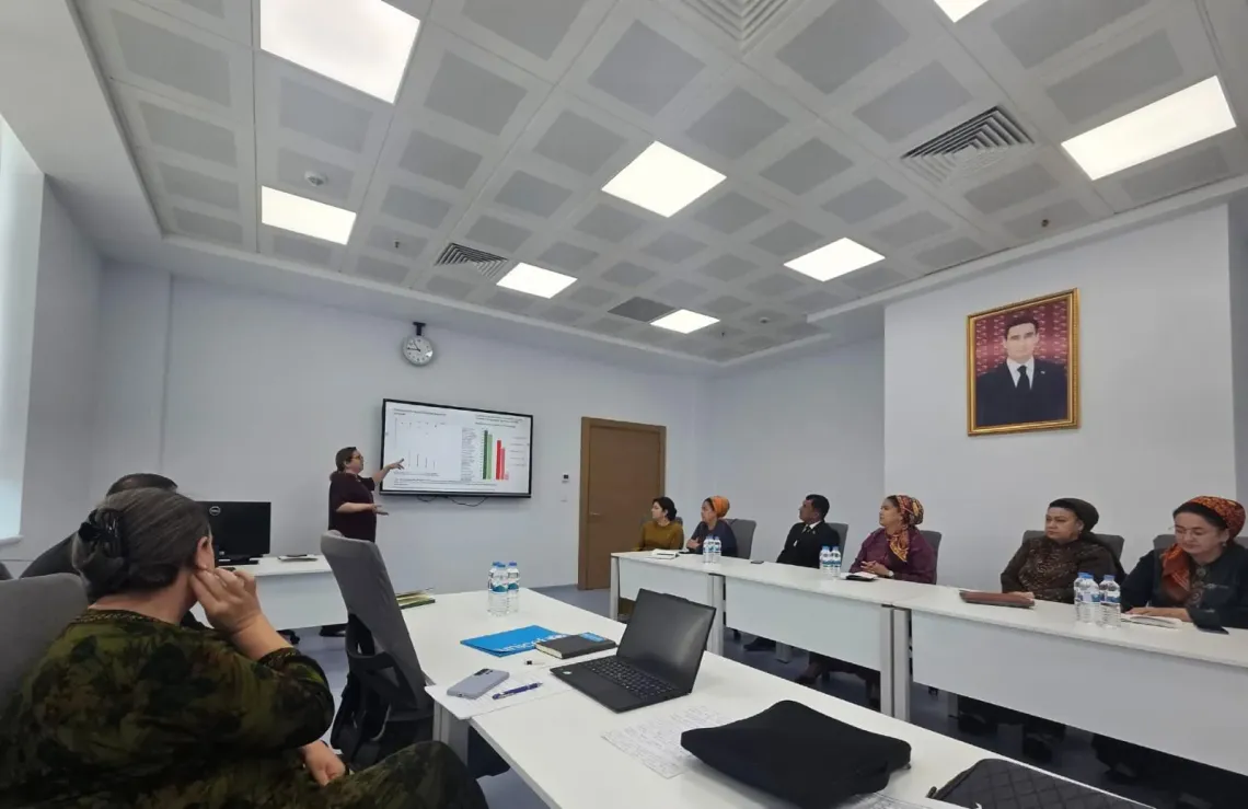 Participants attend a meeting and a woman presenting in front of them