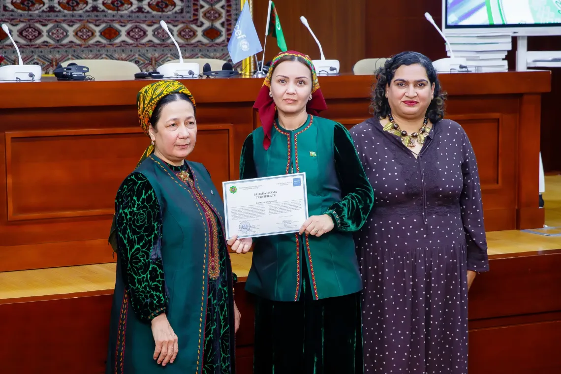 A training participant poses with her professional certification alongside UNICEF Representative Jalpa Ratna and a national partner.