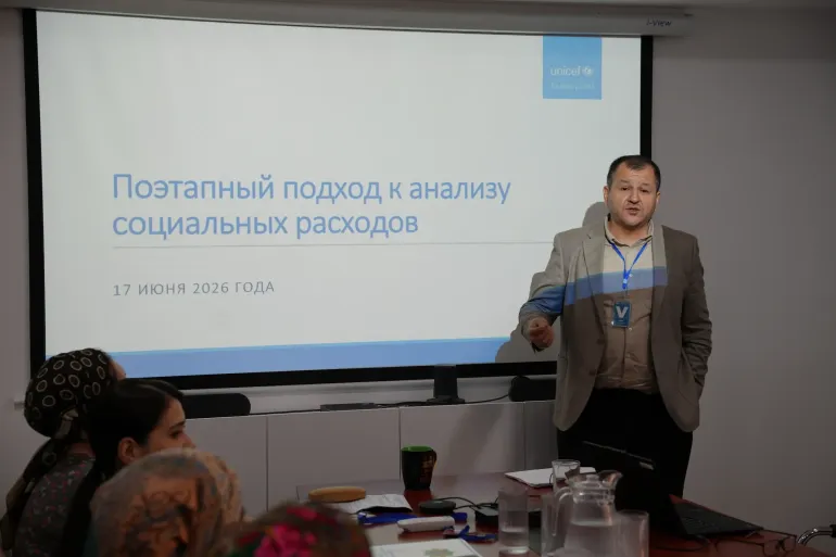 A male presenter delivering a presentation next to a projector screen displaying Russian text titled "A step-by-step approach to social spending analysis" with a UNICEF logo.