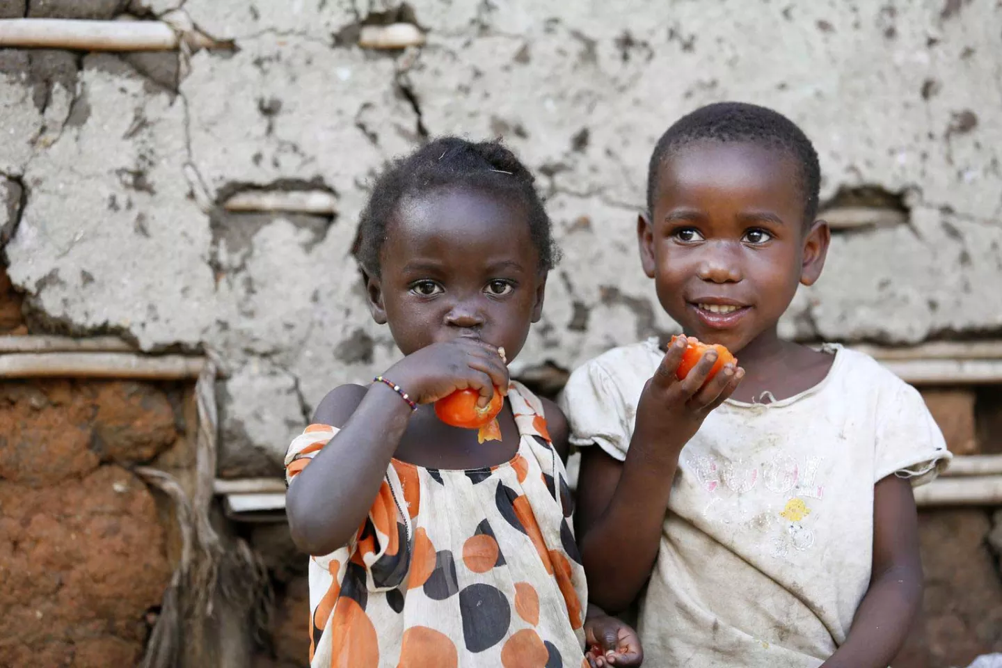 A boy and a girl eating tomatoes