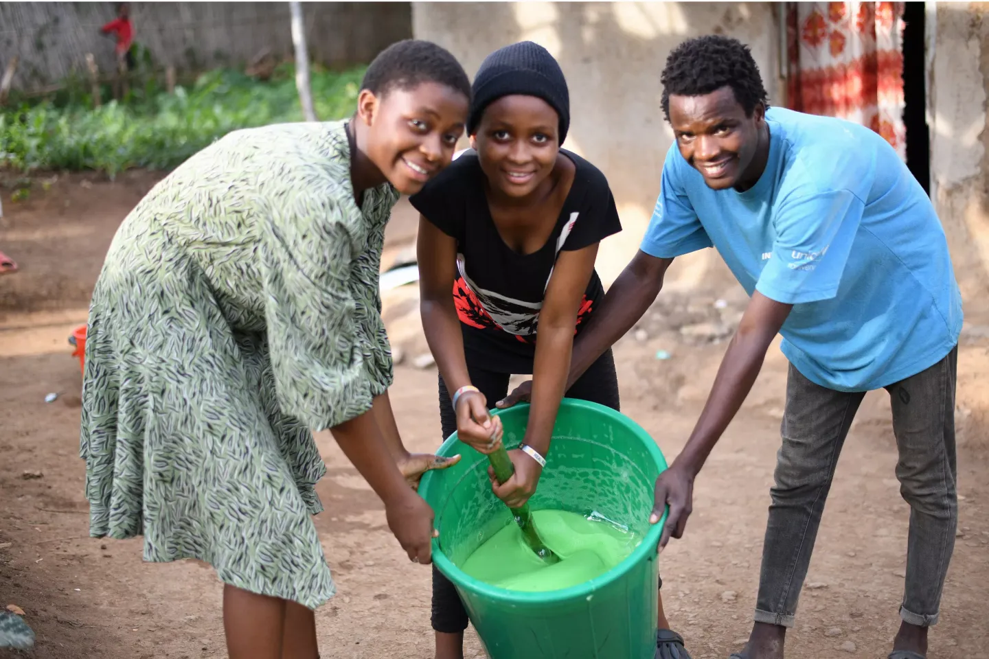 Grace Mongolia, Daniela Esther, and Jordan Shukuru Mugenyi, out-of-school youths in the Kyangwali Refugee Settlement in Kasonga Block 29, make liquid soap to sell in the settlement. The trio are beneficiaries of the UNICEF-funded UPSHIFT program, which offers transferable skills such as social entrepreneurship.