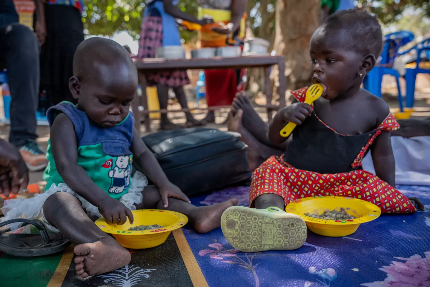 Children eating prepared food in the complementary food bowls. Empowering change: Care group volunteers in Adjumani, Uganda, lead nutrition dialogues and cooking demonstrations, 'becoming nutrition doctors' in their communities.