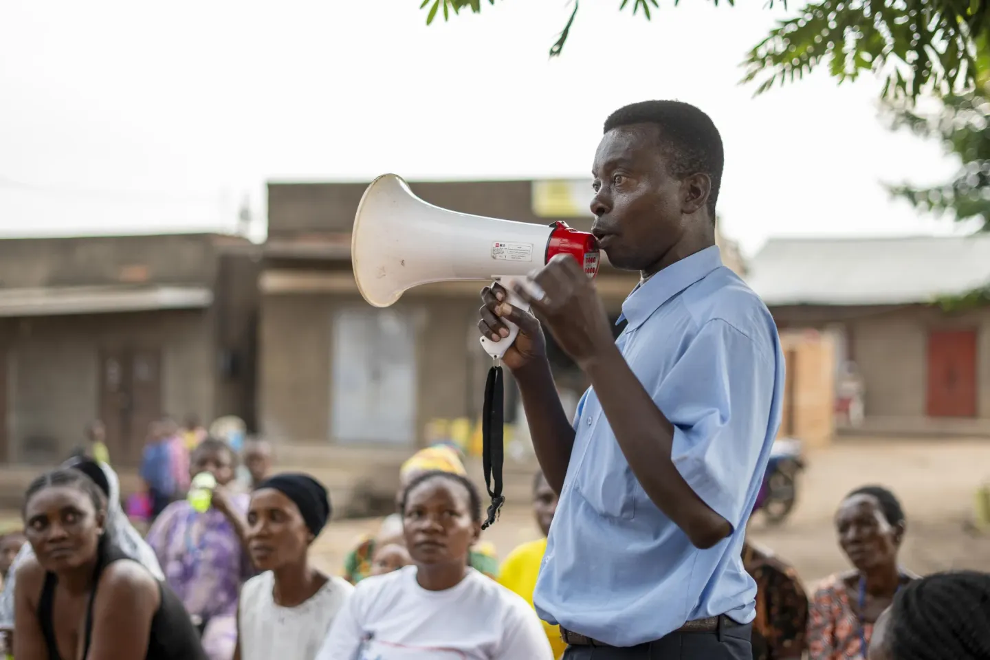 A Village Health Team (VHT) volunteer uses a megaphone to deliver Ebola prevention messages in the local language during a community engagement session in Kasese Town Council, Kasese District.